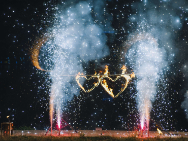 A burning fiery heart, sparks, decorations from an outdoor fire show. Beautiful and bright fireworks in nature on a festive day at a wedding. Gift for newlyweds.